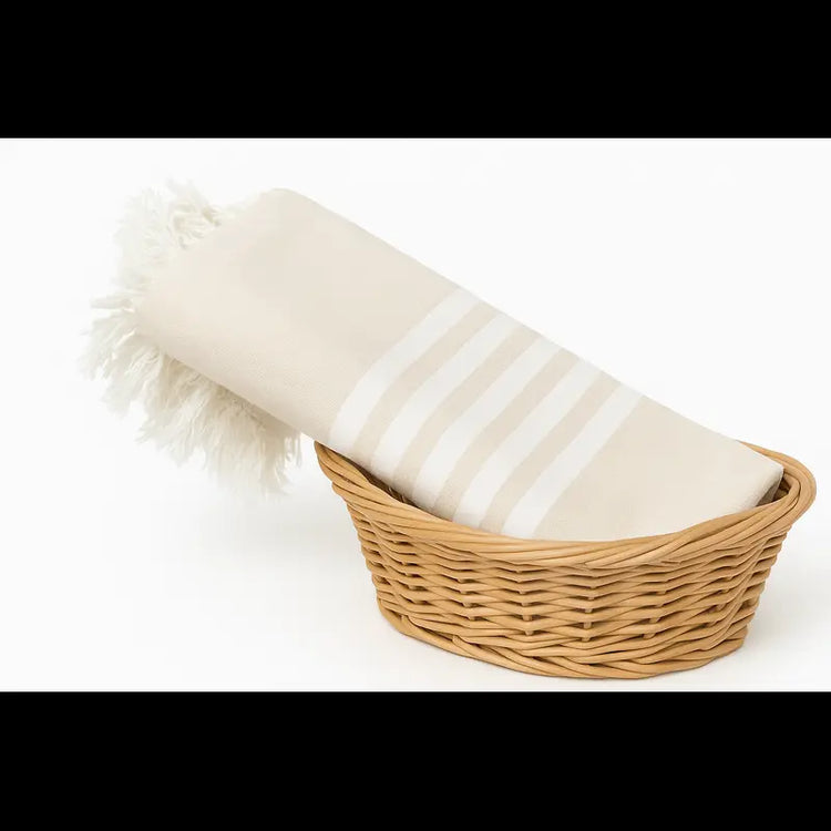 Wicker basket with a white blanket and fluffy white pillow on a white background