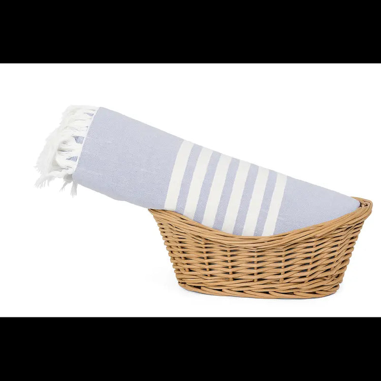 Woven basket with a striped towel inside on a white background