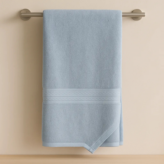 Blue towel hanging on a silver towel rack against a beige wall.