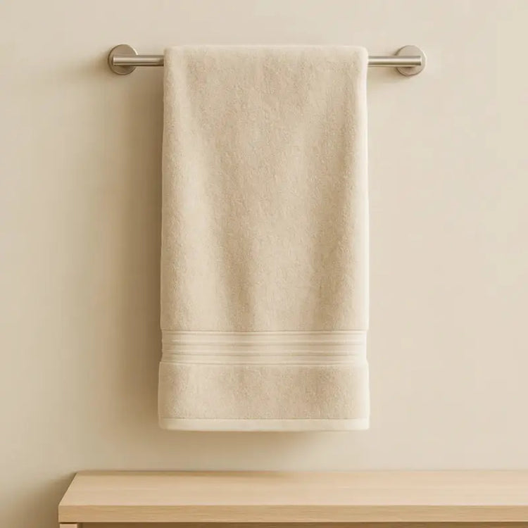 Beige towel hanging on a towel rack against a beige wall.