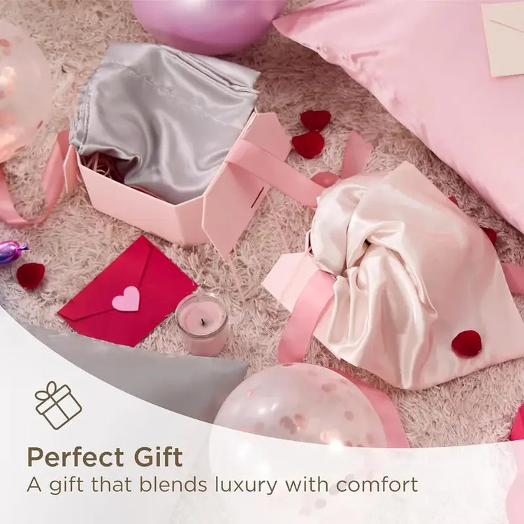 Gift box with pink satin bag, heart-shaped candle, and balloons on a textured surface.