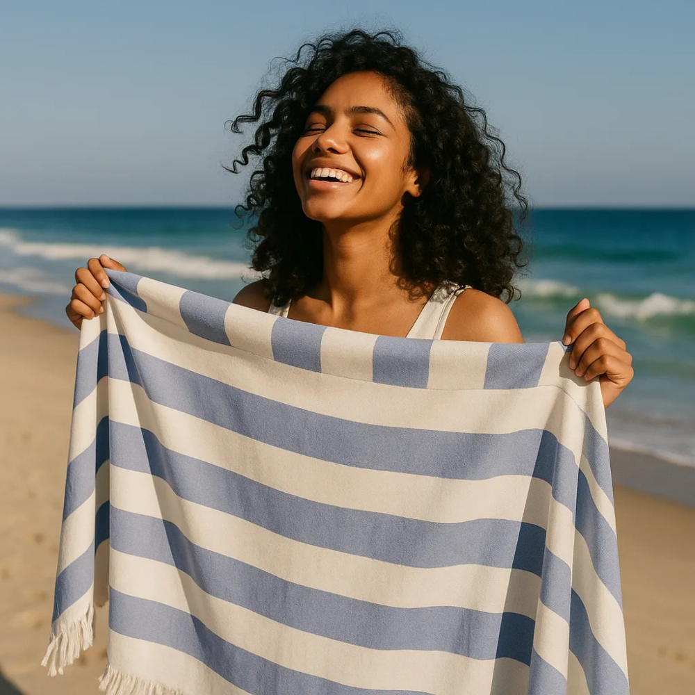 Woman holding a blue and white striped towel on a beach