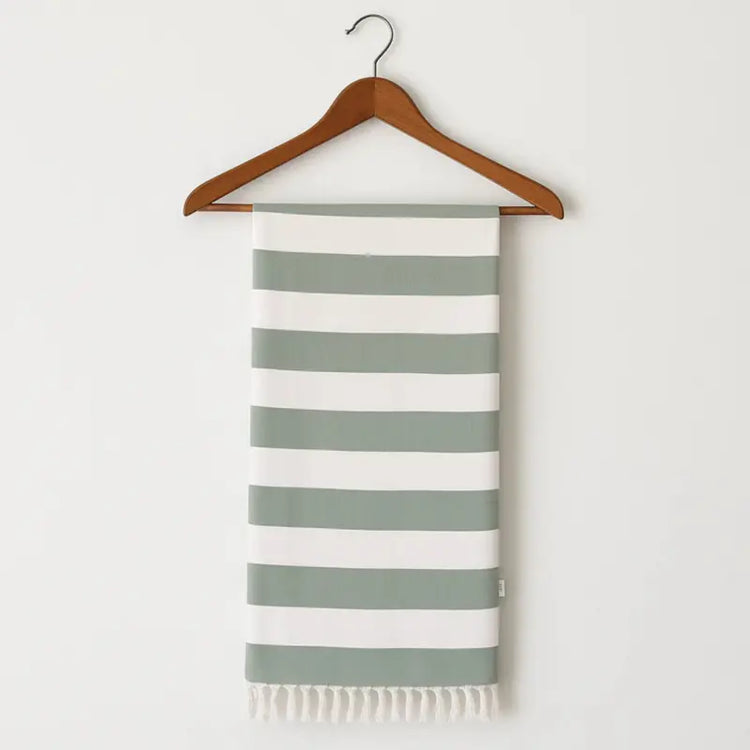Striped towel with green and white stripes on a wooden hanger against a white background