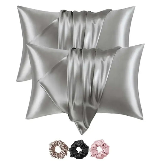Two silver satin pillowcases with three hair scrunchies on a white background