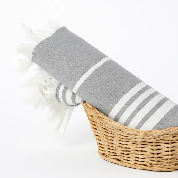 Gray towel with white stripes in a wicker basket on a white background