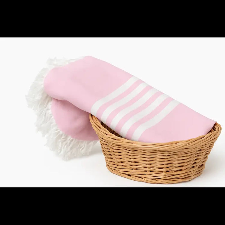 Pink towel with white stripes in a wicker basket on a white background