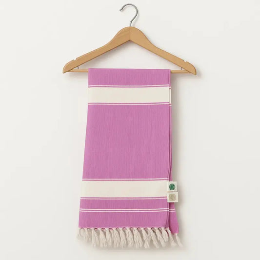 Purple towel with white stripes and fringes on a wooden hanger against a white background