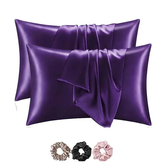 Two purple satin pillowcases with three scrunchies on a white background