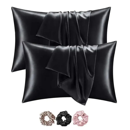 Black satin pillowcases with black, pink, and gold scrunchies on a white background