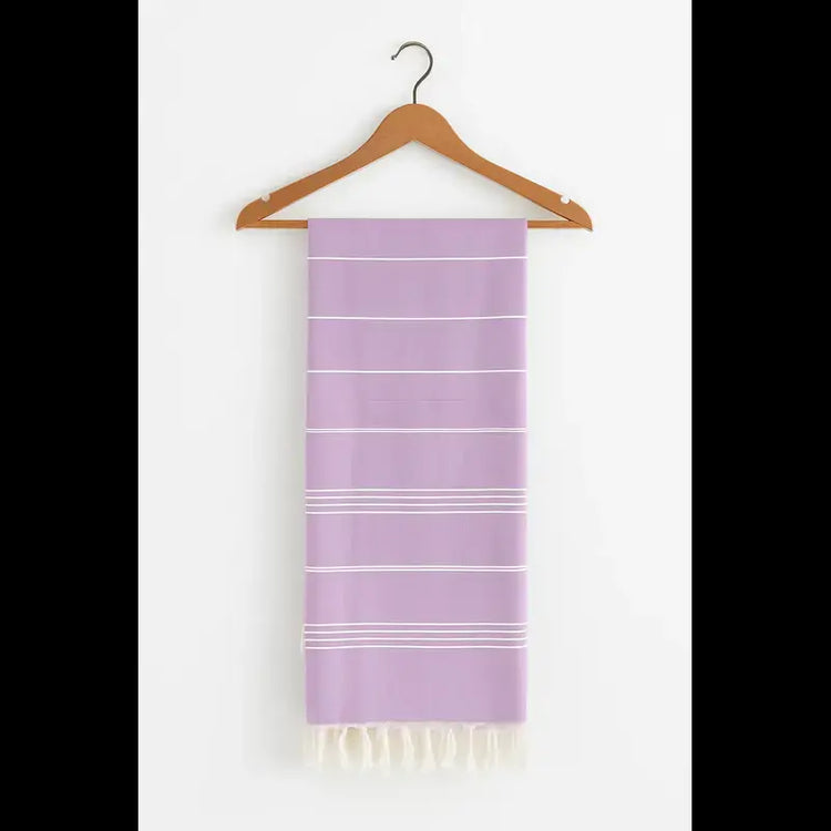 Lavender towel with white stripes and fringes on a wooden hanger against a white background