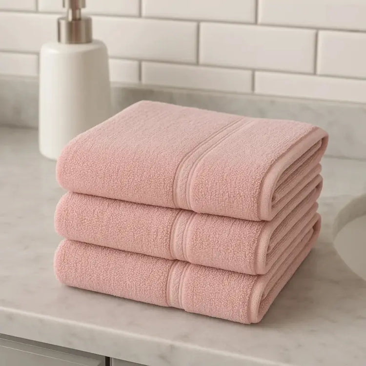 Stack of pink towels on a bathroom counter with a tiled wall background