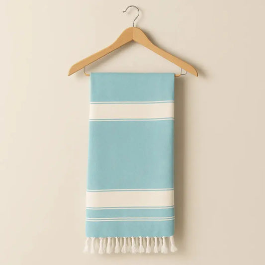 Blue and white striped towel with fringes on a wooden hanger against a beige background