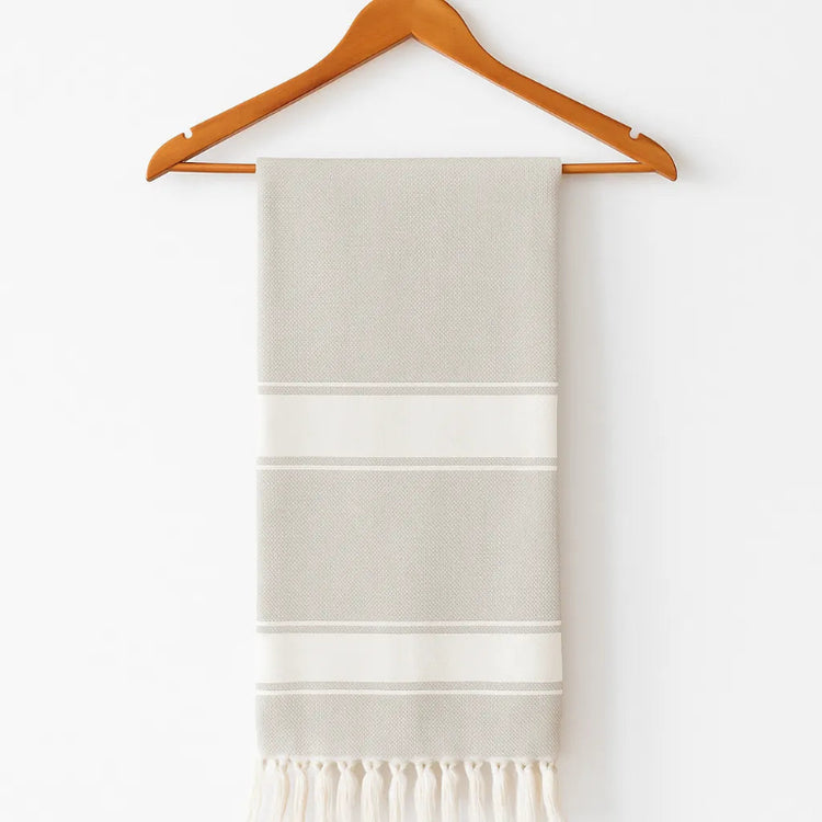 Folded towel with stripes on a wooden hanger against a white background