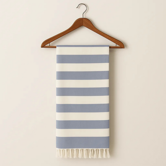 Striped towel with blue and white stripes hanging on a wooden hanger against a beige background