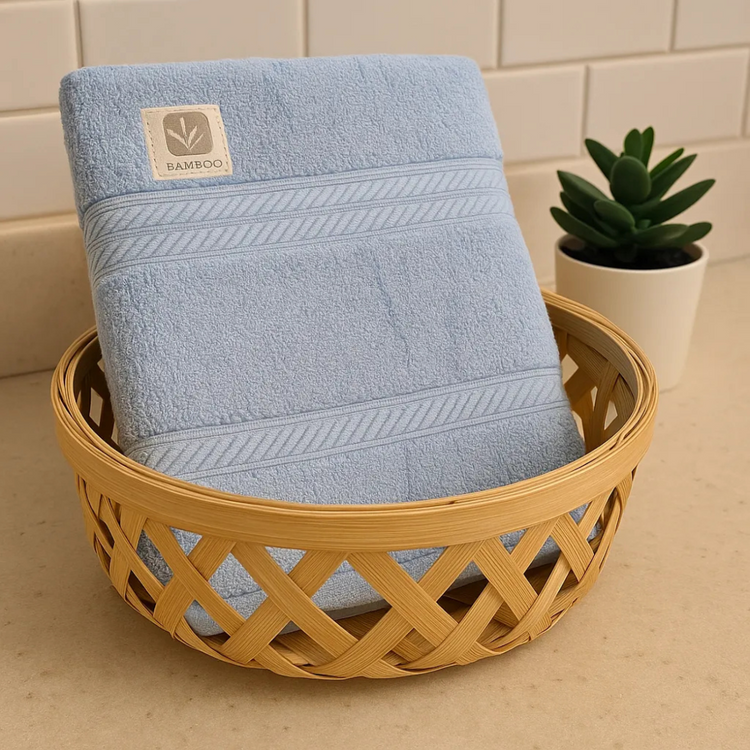 Blue towel with bamboo label in a woven basket on a tiled bathroom floor.