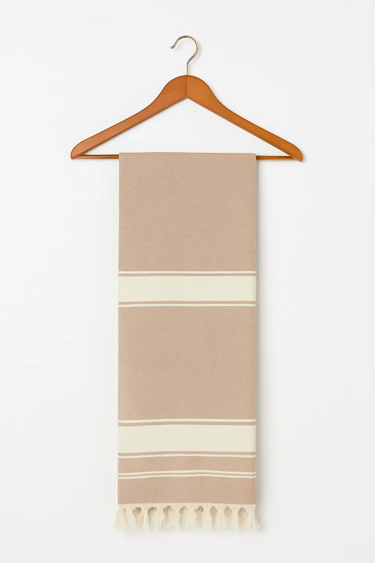 Brown and white striped towel on a wooden hanger against a white background