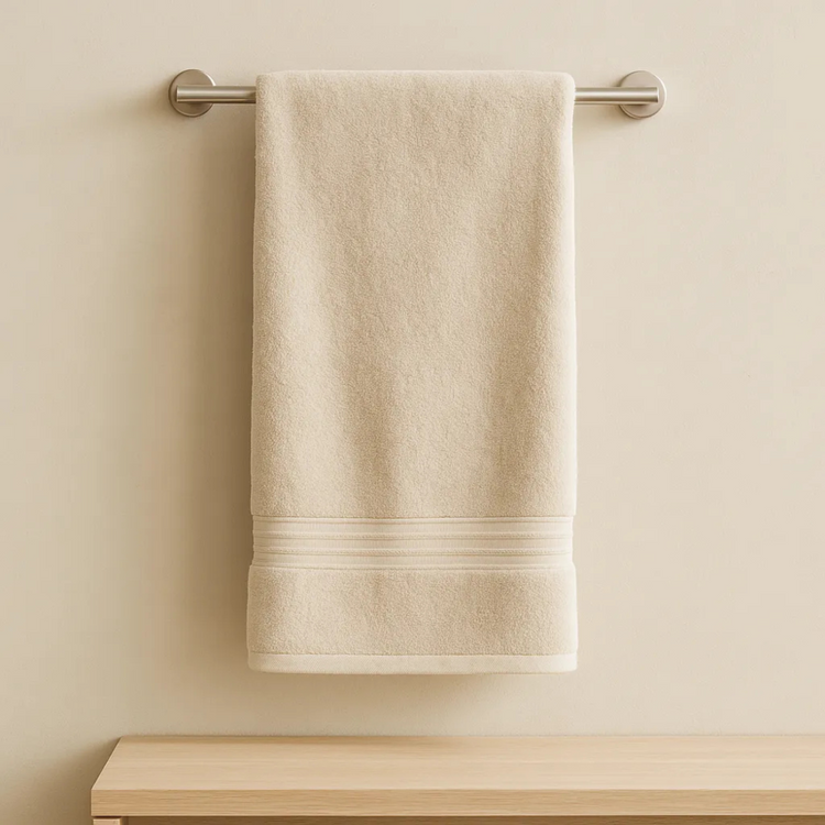 Beige towel hanging on a towel rack against a beige wall.