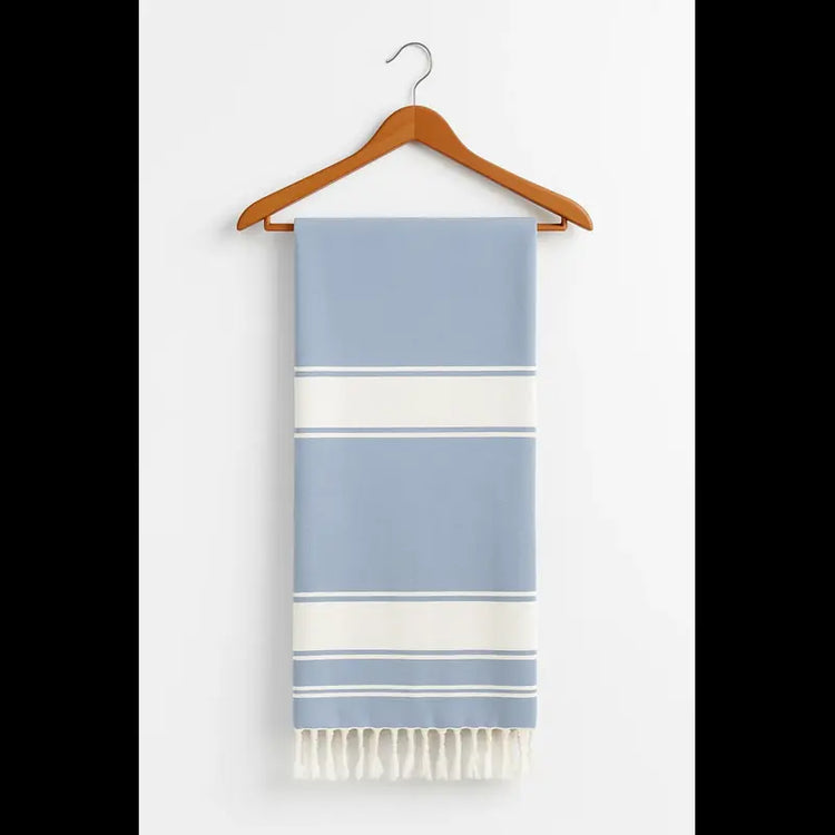 Striped towel with blue and white colors hanging on a wooden hanger against a white background