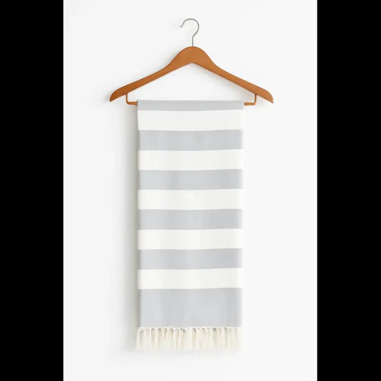 Striped towel with white and gray horizontal stripes on a wooden hanger against a white background