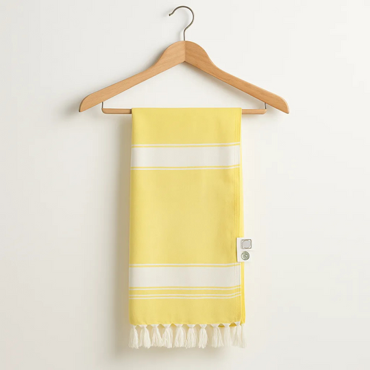 Yellow towel with white stripes and fringes on a wooden hanger against a white background