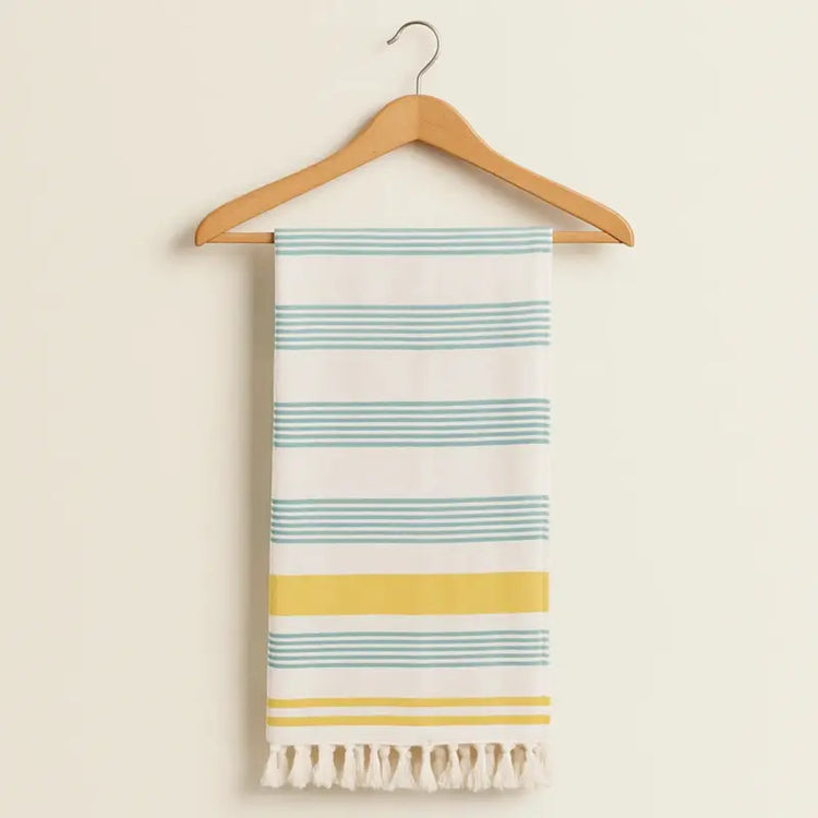 Striped towel with tassels on a wooden hanger against a beige background